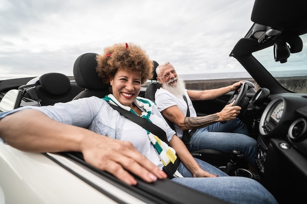 Trendiges Seniorenpaar, das sich während der Sommerferien im Cabrio-Auto amüsiert - Konzentrieren Sie sich auf das Gesicht der Frau