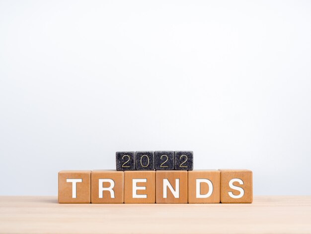 Trends 2022 Business-Hintergrund-Konzept. Die Kalenderjahreszahl 2022 auf schwarzen Würfeln auf Wörtern, Trends auf hölzernen Würfelblöcken auf dem Schreibtisch und weißem Hintergrund mit Kopienraum, einfachem und minimalistischem Stil.