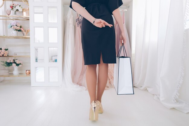 Trendsetterer Lebensstil. Abgeschnittene Aufnahme, Rückansicht einer Frau, die mit gekreuzten Daumen zur Boutique geht, um das perfekte Abendkleid zu finden.