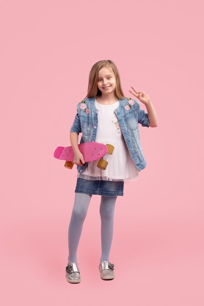 Trendy kleines Mädchen gegen rosa Hintergrund
