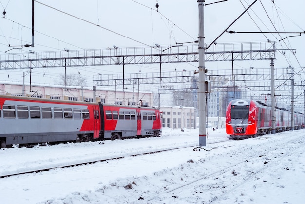Trenes de unidades múltiples diésel y eléctrico cubiertos de hielo se encuentran cerca en el cruce ferroviario en invierno
