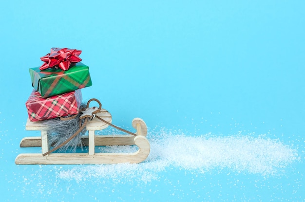 Foto trenó com presentes de natal e ano novo em um fundo azul com neve com espaço de cópia