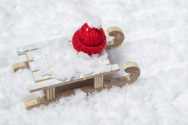 Trenó de madeira de estilo retro com tampa vermelha de Natal em fundo nevado. Brinquedos de Natal, conceito de celebração de inverno.