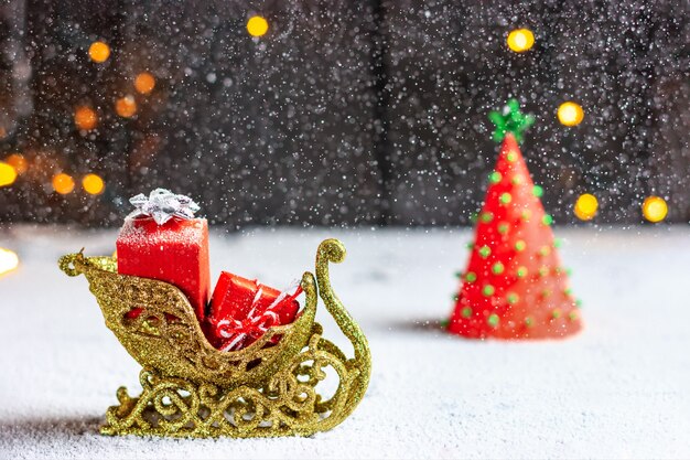 Foto trenó do papai noel com presentes forte nevasca e árvore de natal clima de natal