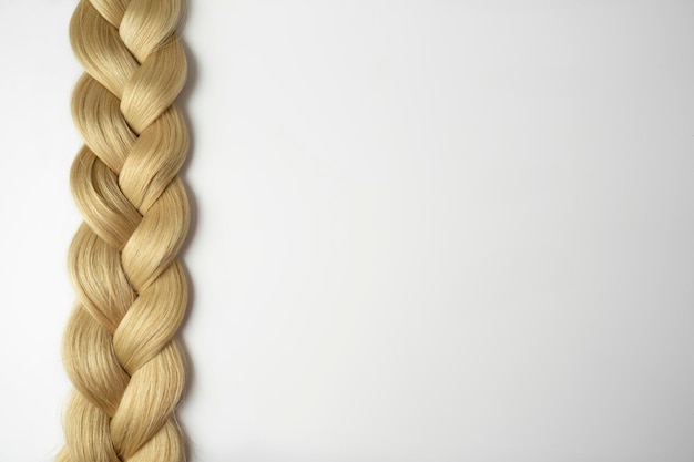 Una trenza rubia acostada sobre un fondo blanco.