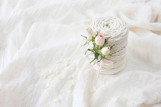 Trenzado de macramé hecho a mano e hilos de algodón con flor rosa sobre sábanas blancas