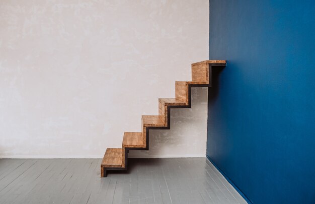 Treppe im Loftstil aus Metall und Holz in der Ecke mit blauer Wand