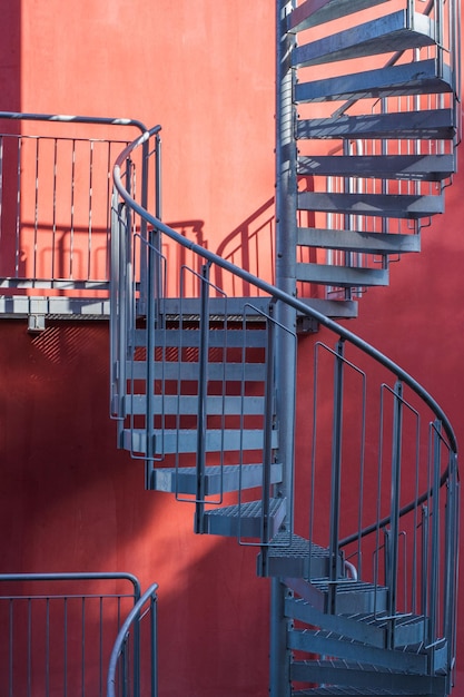 Treppe und Schatten Graue Metalltreppe neben der Wand des orangefarbenen Gebäudes