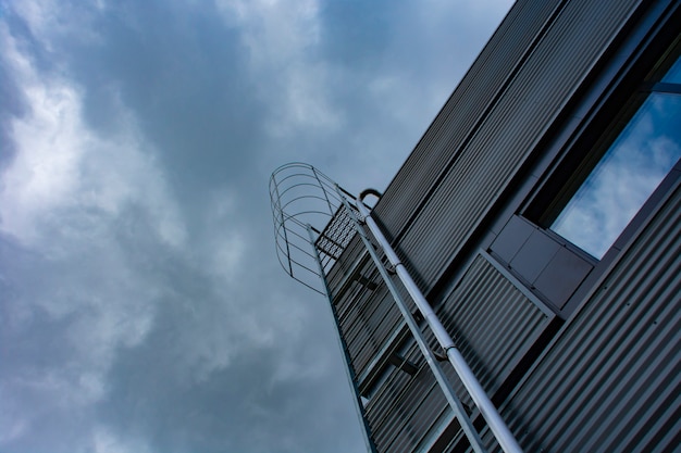 Treppe zum Himmel. Metalltreppe am Gebäude vor dem Hintergrund des Himmels und der Wolken.