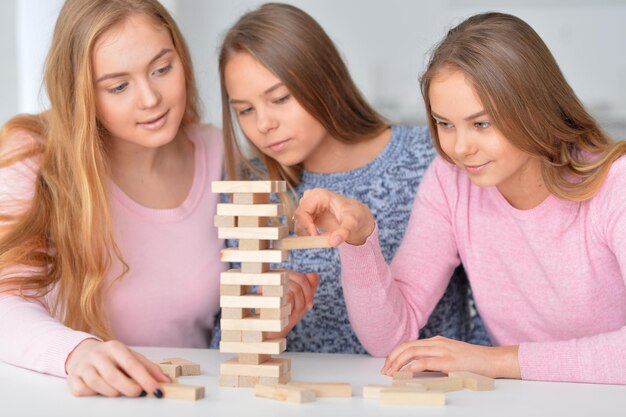 Três adolescentes brincando com blocos de madeira