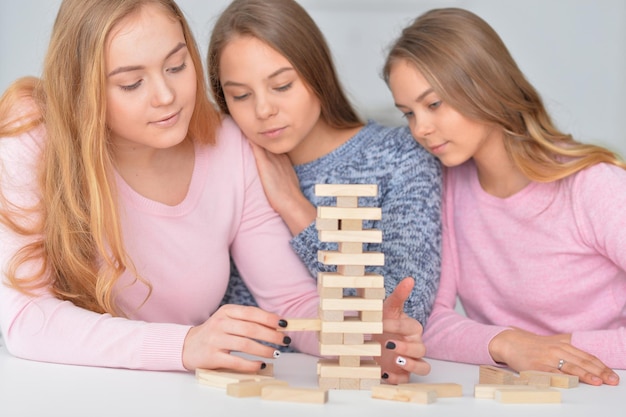 Três adolescentes brincando com blocos de madeira