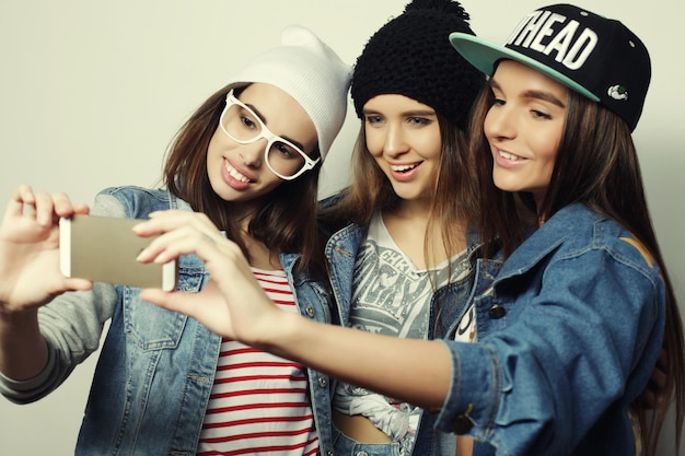 Foto tres adolescentes felices con smartphone tomando selfie