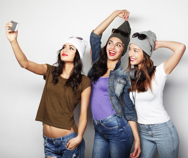 Tres adolescentes felices con smartphone tomando selfie