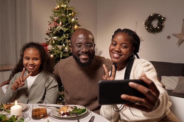 Três africanos fazendo selfie em uma mesa festiva no dia de Natal