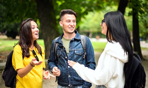 Três alunos conversando ao ar livre em um pátio da faculdade