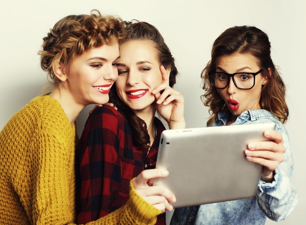 Tres amigas adolescentes tomando selfie con tableta digital