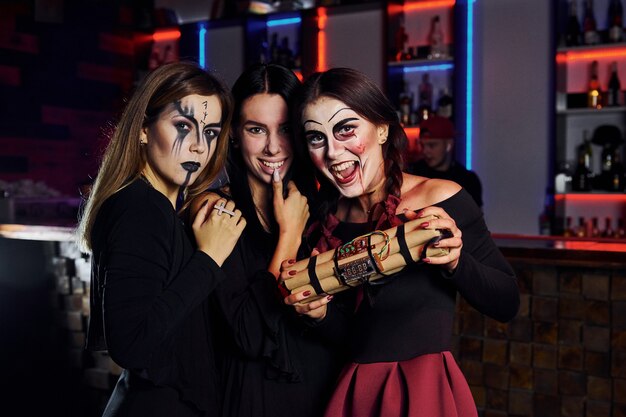 Três amigas estão na festa de halloween temática com maquiagem e fantasias assustadoras.