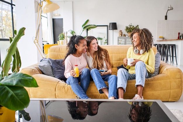 Foto tres amigas felices sonriendo y divirtiéndose en casa mujeres divertidas juntas celebrando sentarse