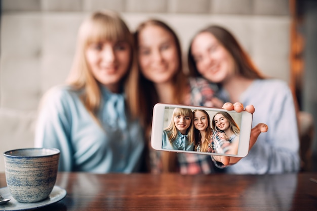 Tres amigas hace selfie en cámara en café