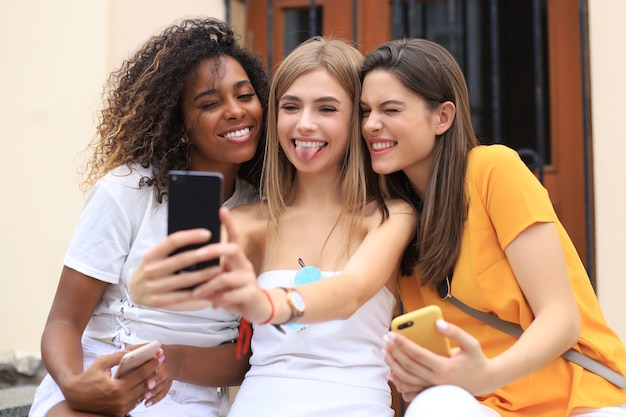 Tres amigas lindas que se divierten juntos, tomando un selfie en la ciudad.