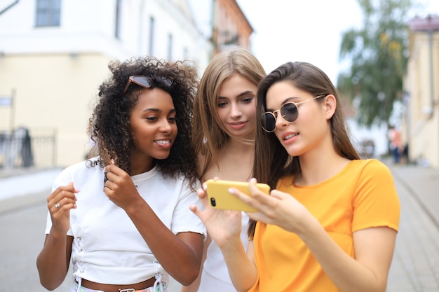 Tres amigas lindas que se divierten juntos, tomando un selfie en la ciudad.