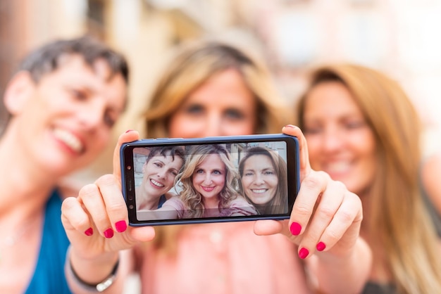 Tres amigas maduras tomando un selfie horizontalmente. Amigos de mediana edad compartiendo tiempo juntos y divirtiéndose.