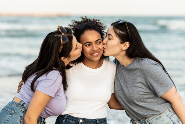 Três amigas se beijando na praia