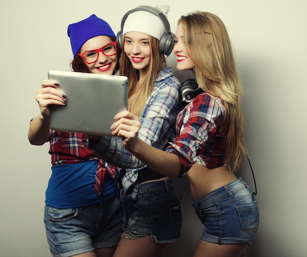 Três amigas tirando uma selfie com um estúdio de tablet digital sobre um fundo cinzento