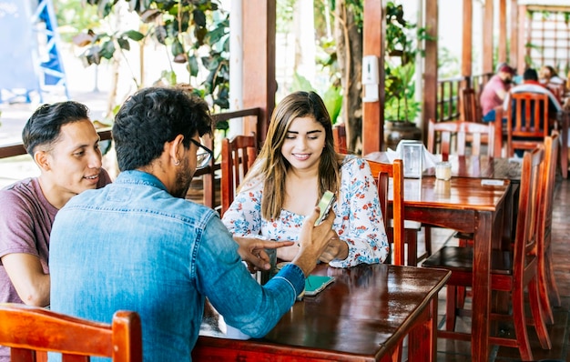 Três amigos adolescentes em seus telefones celulares em um café Jovens amigos em um café com seus celulares se divertindo Três pessoas em um café com telefones se divertindo