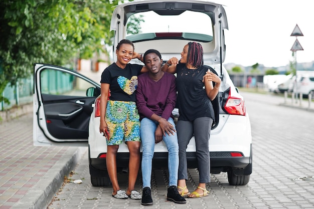 Três amigos afro-americanos sentam-se no porta-malas do carro