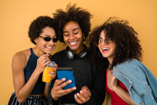 Três amigos afro usando telefone celular