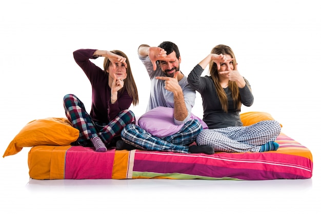 Foto tres amigos en una cama enfocando con sus dedos