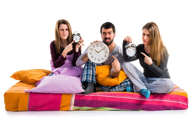 Tres amigos en una cama con reloj vintage