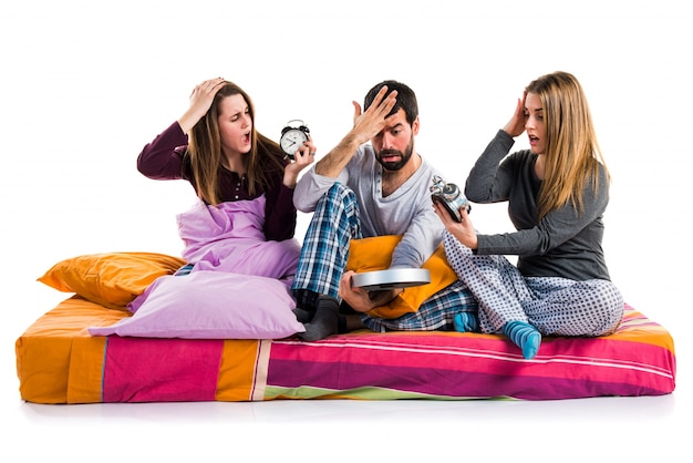 Tres amigos en una cama con reloj vintage