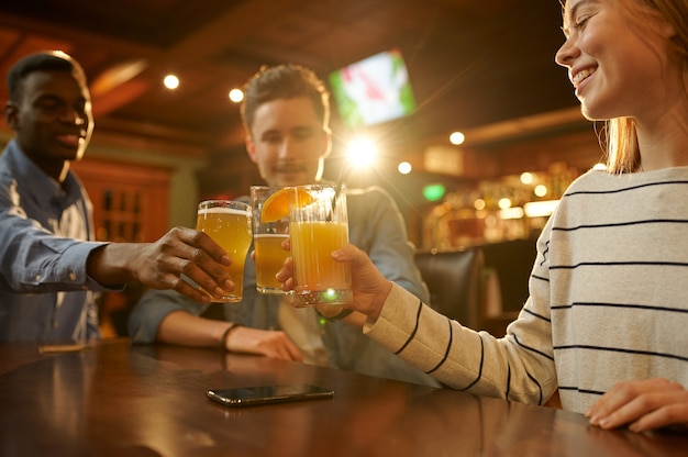 Três amigos com bebidas alcoólicas se divertindo na mesa do bar. grupo de pessoas relaxando no bar, estilo de vida noturno, amizade, celebração de evento