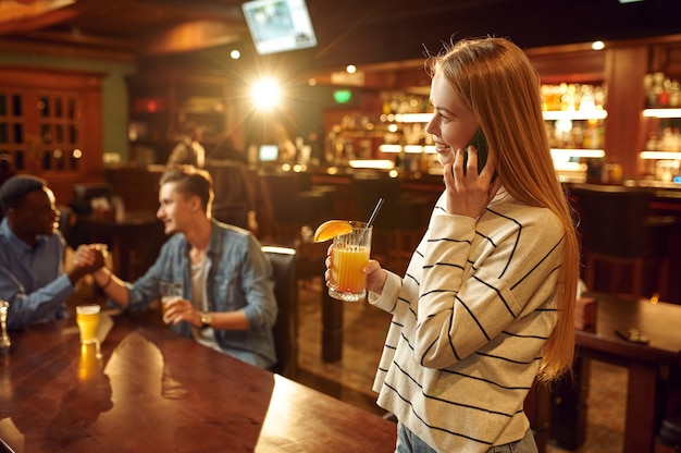 Três amigos com bebidas alcoólicas se divertindo na mesa do bar. Grupo de pessoas relaxando no bar, estilo de vida noturno, amizade, celebração de evento