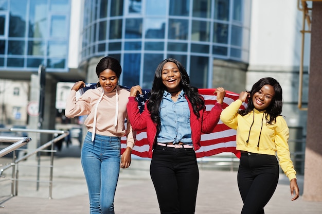 Três amigos da mulher afro-americana jovem faculdade com bandeira dos EUA.