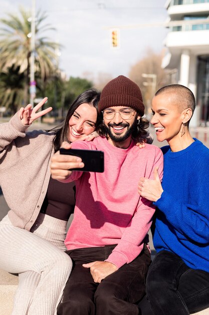 Foto tres amigos divertidos tomándose un selfie en la ciudad