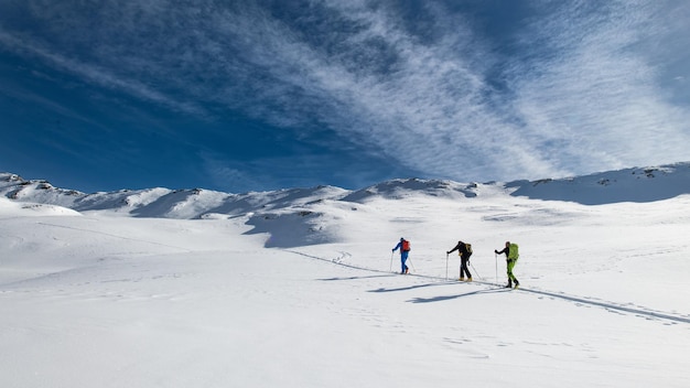 Três amigos durante uma viagem de alpinismo de esqui na trilha