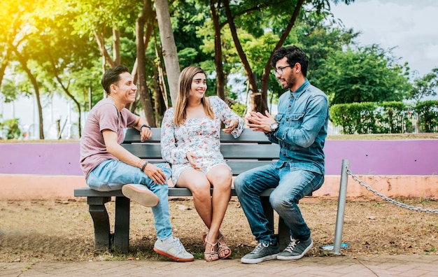 Tres amigos felices hablando en un parque Tres amigos adolescentes hablando sentados en un banco del parque Grupo de tres amigos hablando sentados en un parque Concepto de gente hablando en el parque