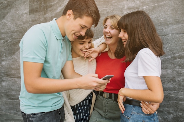 Três amigos felizes rindo muito assistindo vídeos na escola.