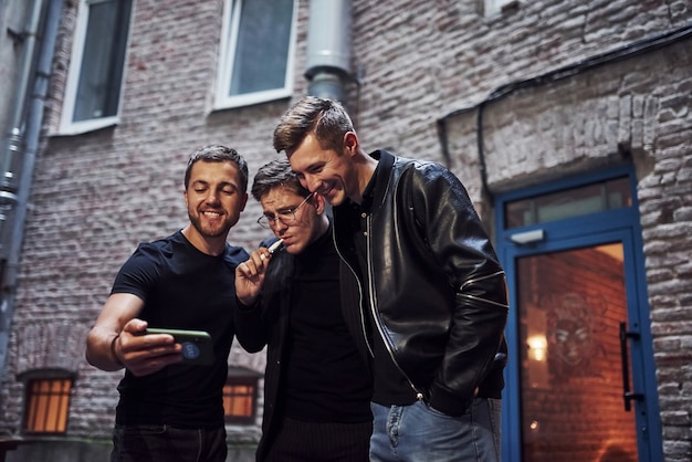 Três amigos homens do lado de fora do bar