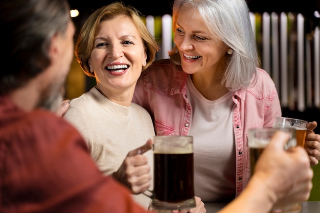 Foto tres amigos mayores bebiendo cerveza y riéndose en un restaurante