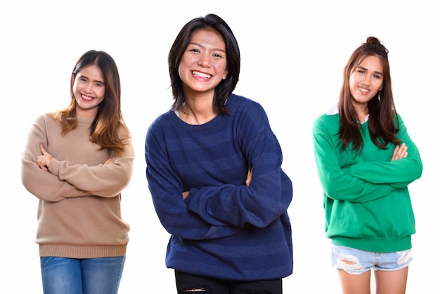 Tres amigos de la mujer asiática joven feliz sonriendo con los brazos cruzados