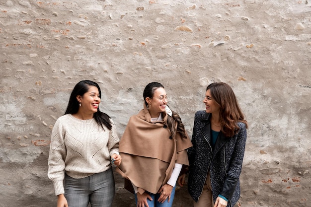 Três amigos rindo. Grupo multirracial de mulheres se divertindo. Antiga muralha da cidade em fundo com espaço de cópia.