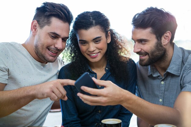 Foto três amigos usando telefone celular na cafeteria