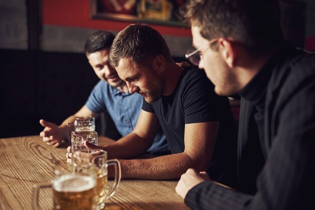 Tres amigos varones en el bar.