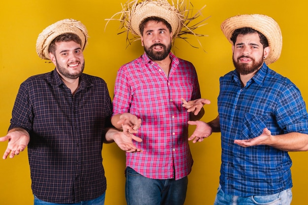 Três amigos vestindo roupas típicas para a Festa Junina Dúvidas questionando