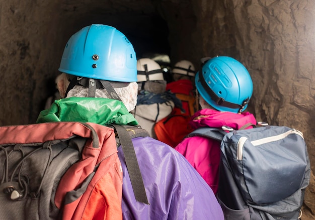 Tres ancianos no identificados entran en la cueva para hacer espeleología. Vestido con ropa especial y seguro.