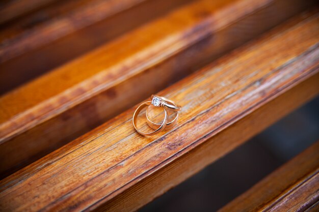 Tres anillos de bodas de oro en un banco de madera